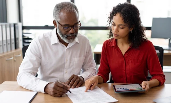 homem e mulher sentados a mesa analisando algumas informações descritas em uma folha, representando: Como estruturar contratos para evitar riscos fiscais