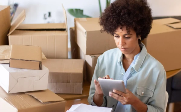 Empreendedora com seu tablete em seu estoque, representando: Como organizar o processo de compras na pequena empresa