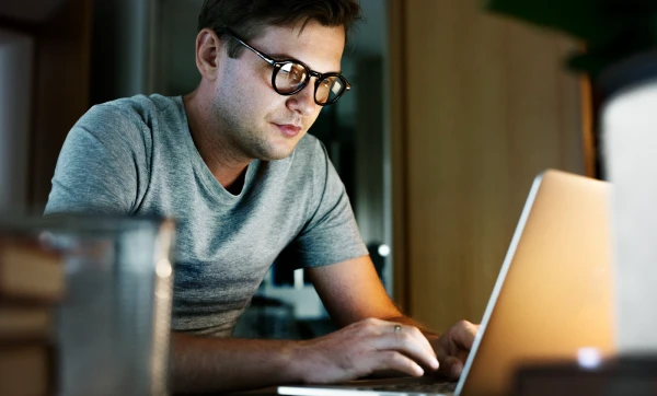 Homem de óculos sentado em frente ao seu notebook, representando: Como usar a ordem de serviço do GestãoClick: guia completo de configuração e uso